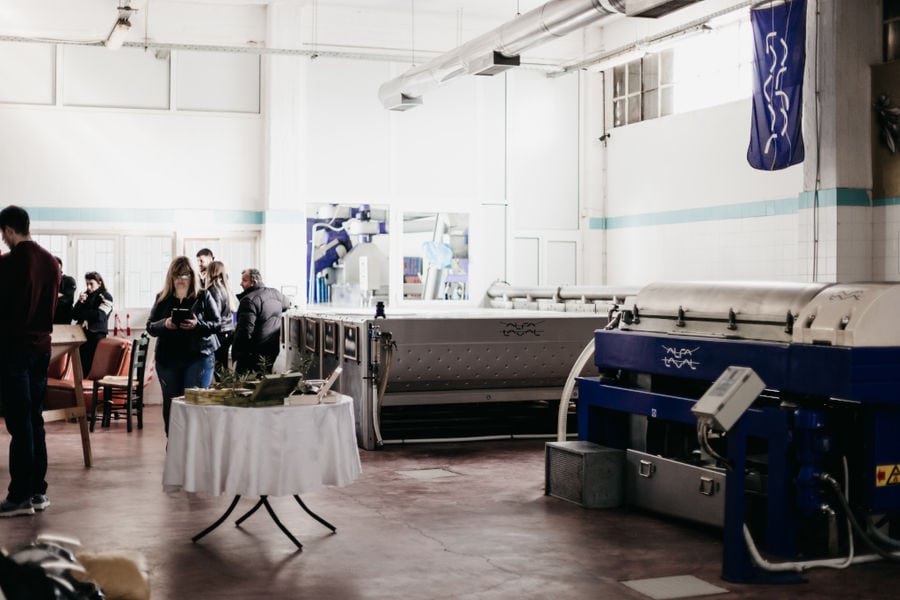 tourists at Konstas Olive Tours plant surrounded by olive oil machines and table with olive oil for tasting