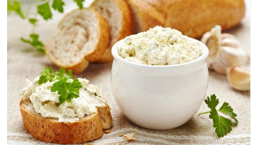 close-up of bowl with Greek ‘Kopanisti’ means soft white cheese and slices of bread in the background