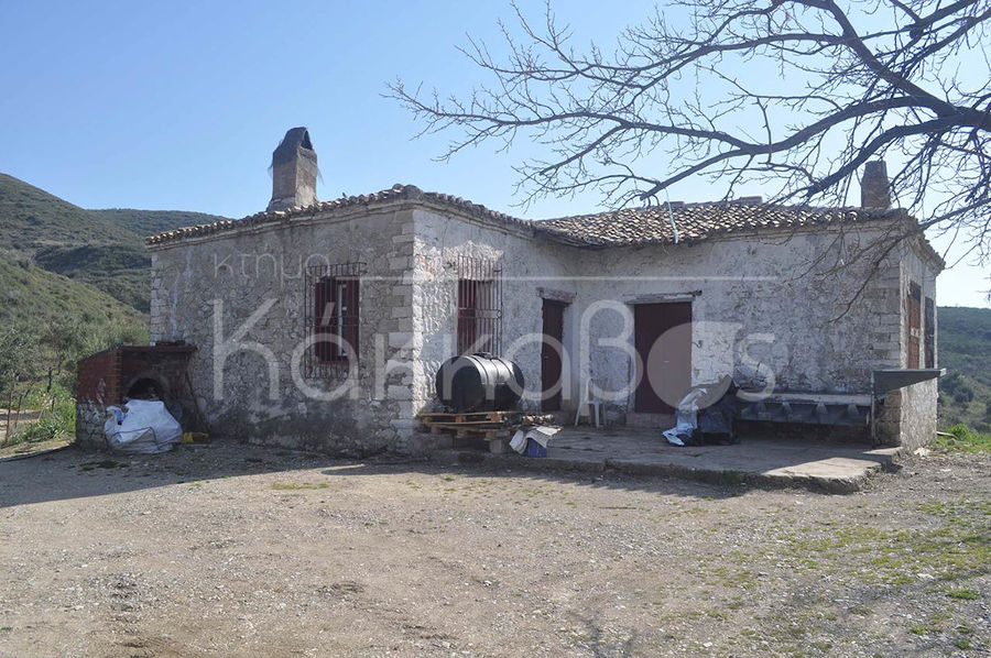 front view of 'Ktima Kakkavos' stone building and the mountains in the background