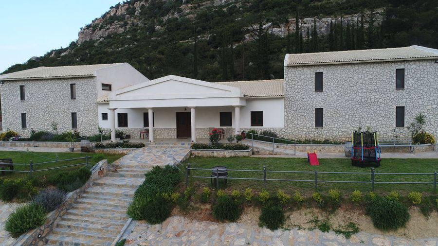front view of Ktima Karamitsos building with stone steps and green lawn on the both sides