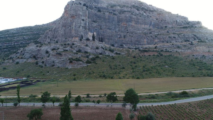 far view of stone mountain with Ktima Karamitsos vineyards and trees in the front