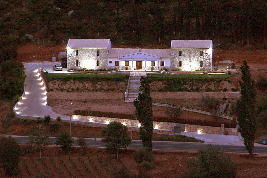 illuminated Ktima Karamitsos building from above with stone steps and green lawn on the both sides by night