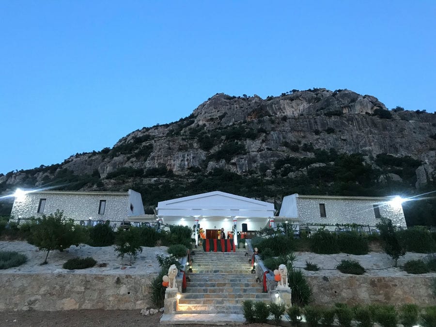 illuminated Ktima Karamitsos building from above with stone steps and green lawn on the both sides by night