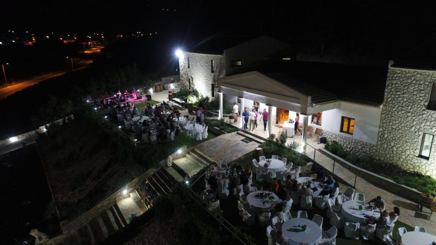 wedding at illuminated Ktima Karamitsos building from above with stone steps and tables with persons on the both sides by night