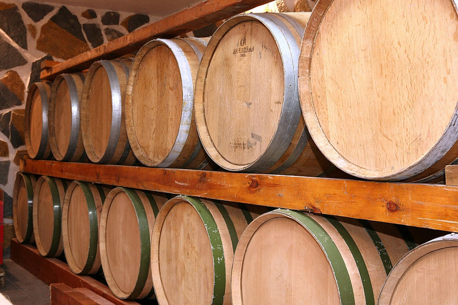 lying wine barrels on top of each other on wood selfs at Ktima Karamitsos stone cellar