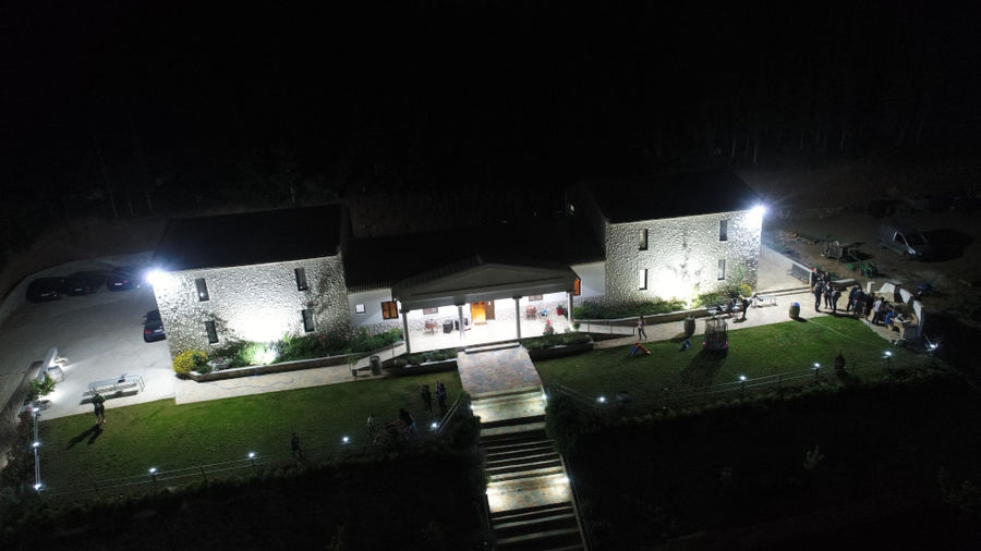 illuminated Ktima Karamitsos building from above with stone steps and green lawn on the both sides by night