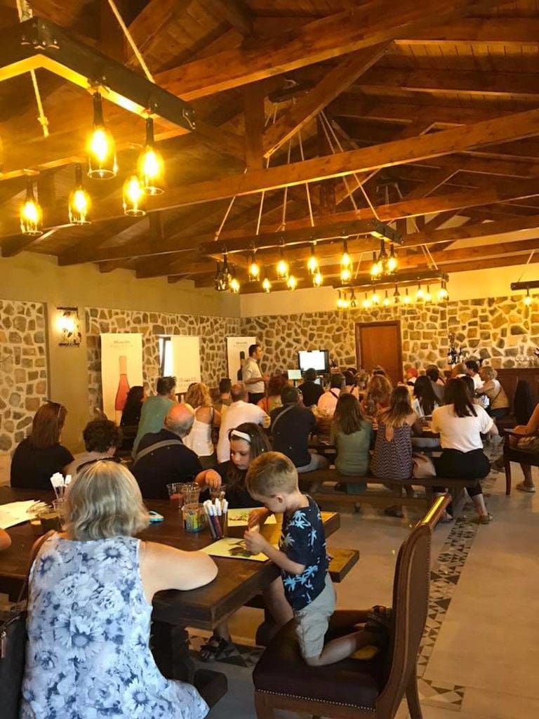 tourists at the wood tables with benches Ktima Karamitsos illuminated tasting room