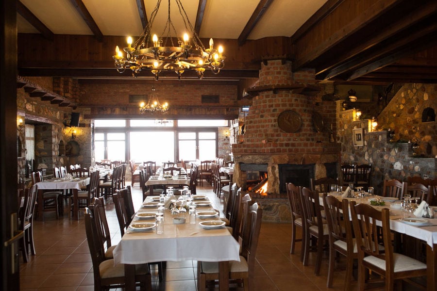 illuminated restaurant of Ktima Perek with tables and chairs and a fireplace