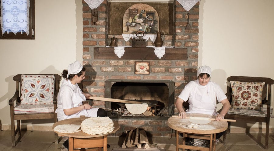 women using wood dough paddles to make pies at Ktima Perek front the stone fireplace
