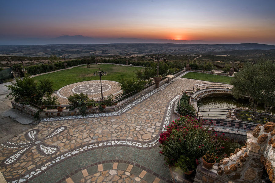 Ktima Perek garden with fountains, trees and pavements in the background of sunset