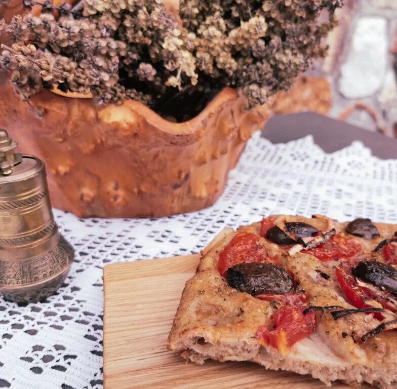 close-up of pice of pizza with cheese, tomatoes and sausage at Ktima Perek
