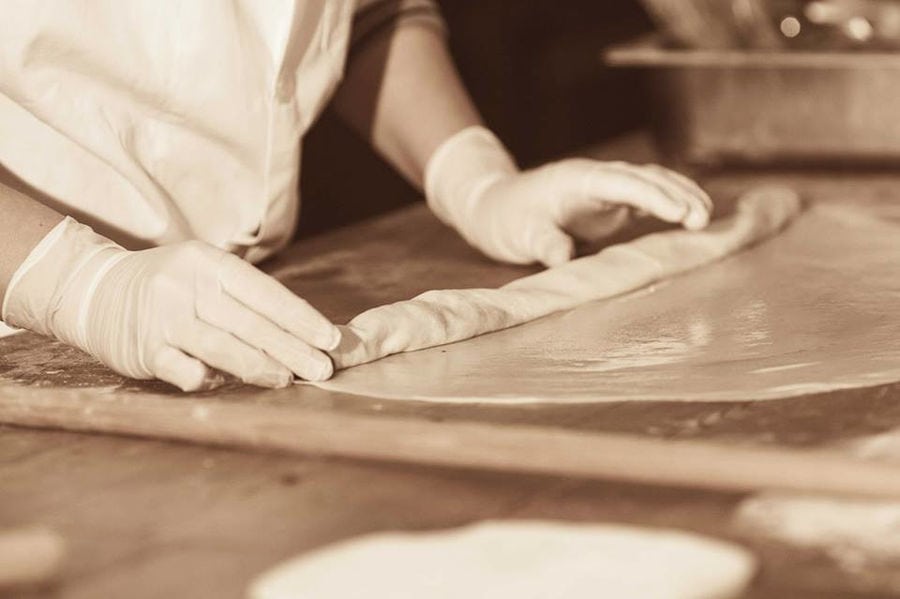 close-up of woman using wood dough paddles to make pies at Ktima Perek workshop