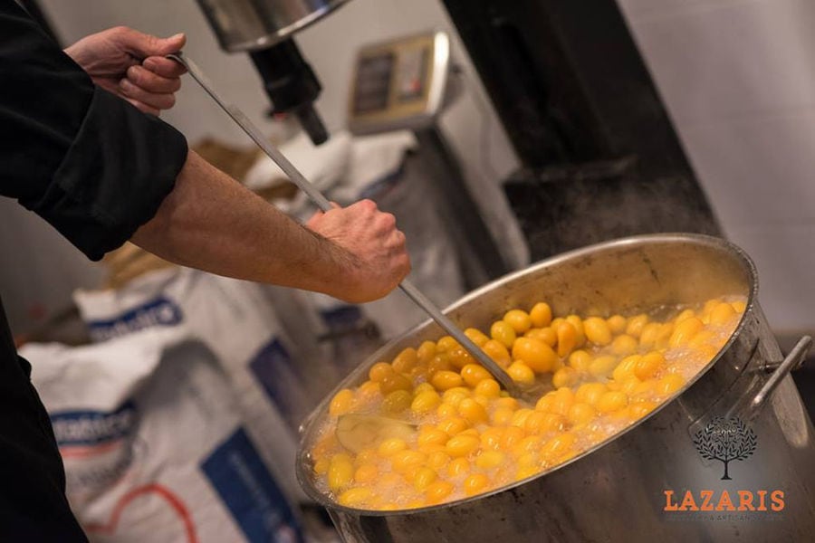 man mixing and boiling liquid composition of kumquat fruits in the cauldron at Lazaris Distillery