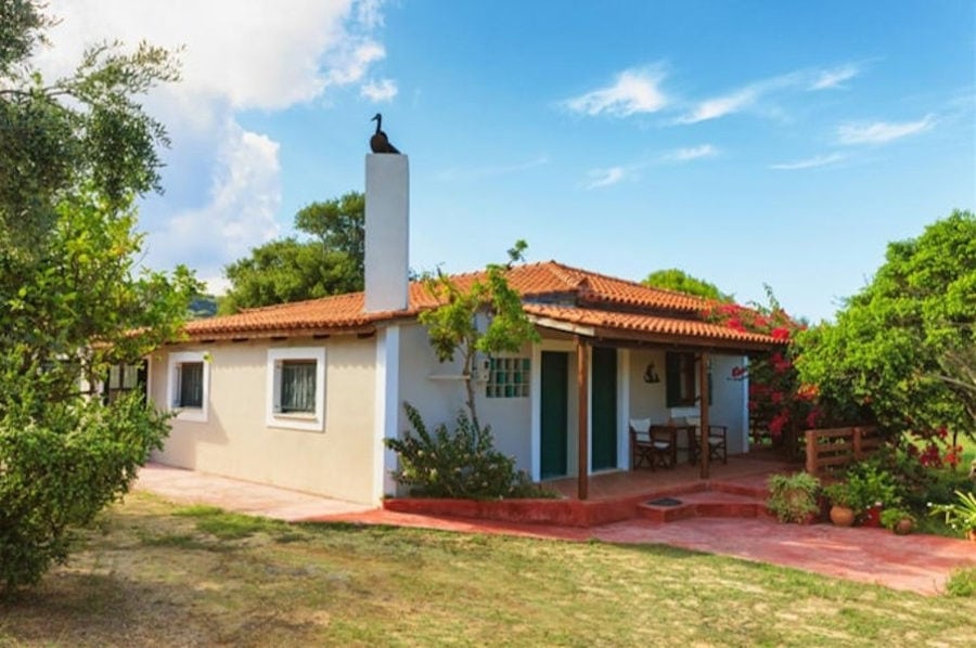 corner of 'Lithies Organic Farm' house surrounded by trees and green grass