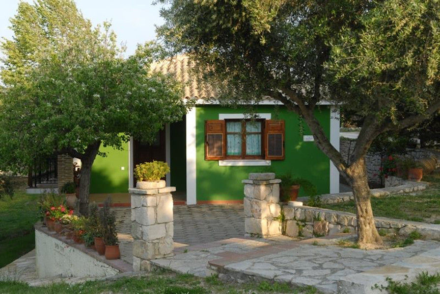 'Lithies Organic Farm' house with green walls and stone pavement and trees in the front