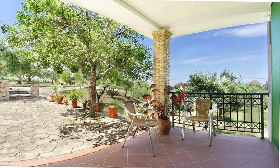 corner of 'Lithies Organic Farm' terrace with two chairs and trees in the background