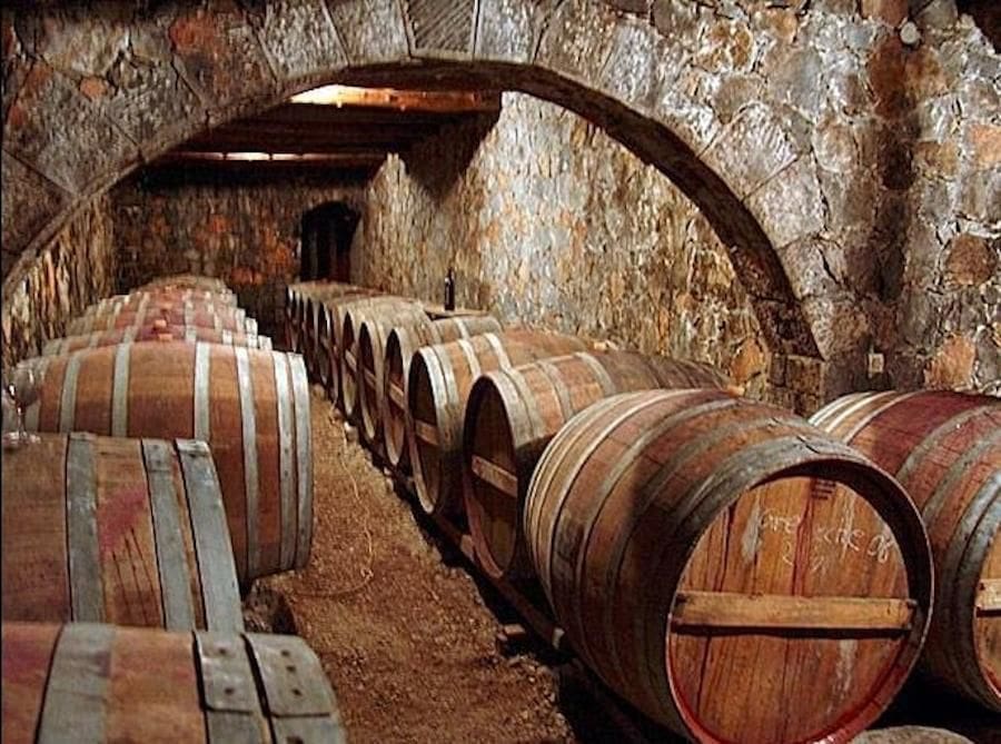 lying wine wood barrels at Dourakis Winery stone cellar with arcade