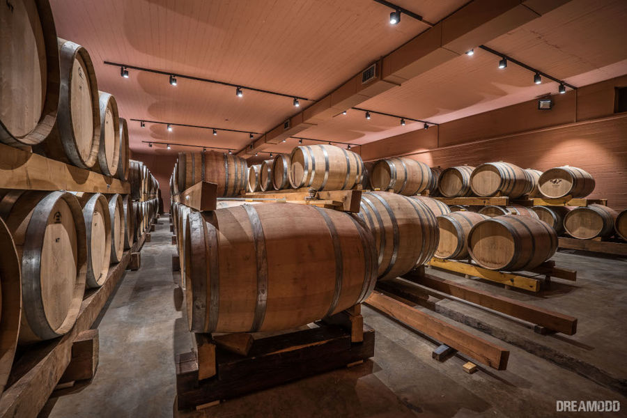 wood barrels on top of each other at illuminated 'Lykos Winery' cellar