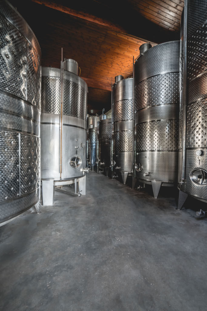 two rows of aluminum wine storage tanks at 'Lykos Winery' plant