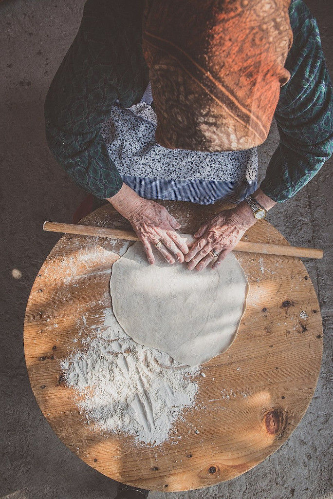 old woman using wood dough paddle to make dough at Maggiri facilities