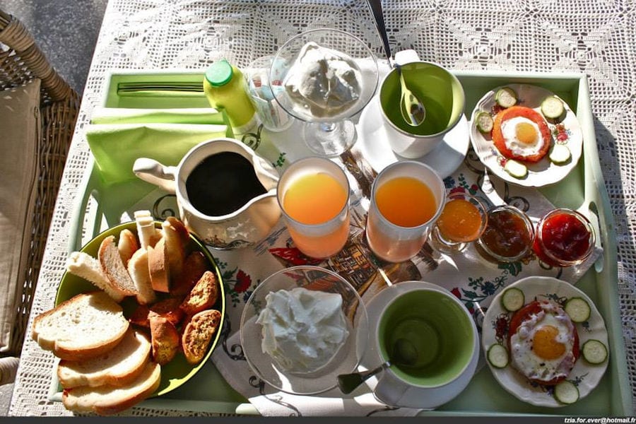 view from above plates with eyes fried eggs and yogurt and slices of bread and glass with juices and 'La Maison Vert Amande'coffee