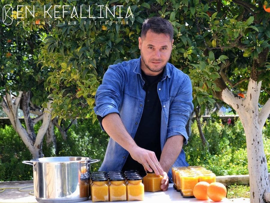a young man watching at the camera and capping of marmelade jars at En Kefallinia Organic Farm Restaurant