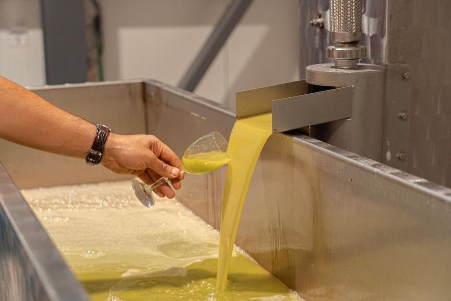 man take with a glass an olive oil sample from the press machine at Politakis Olive Oil Mill premises