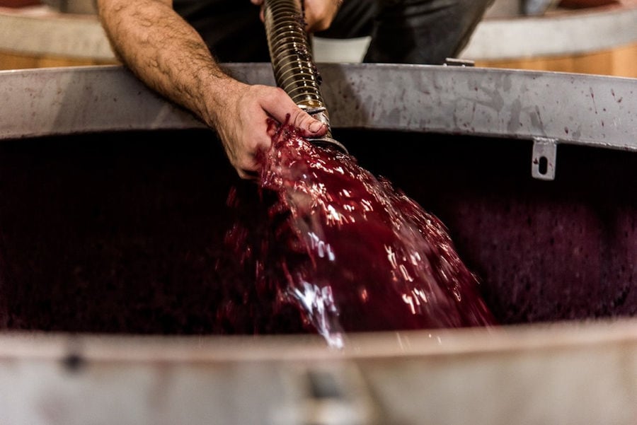 red wine 'must' flowed from the hydraulic pump that holding it a man at Manousakis Winery plant