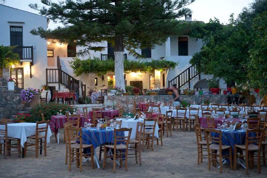 tables with folklore cloths and chairs in the front of illuminated Manousakis Winery restaurant
