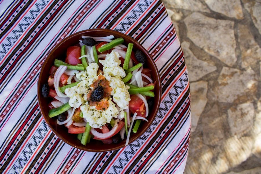 ceramic bowl with salad with tomatoes, olives, cucumber with cheese on the top on the table at Manousakis Winery restaurant