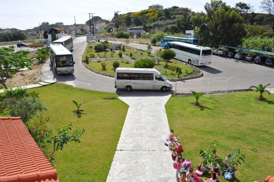 parked buses around a large flower bed at 'Melissokomiki Dodekanisou Bee Museum'