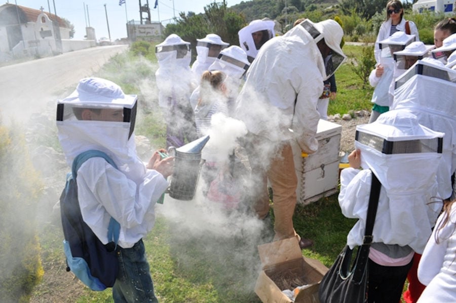 kids dressed as beekeepers and a teacher holding a beehive smoker at Melissokomiki Dodekanisou Bee Museum