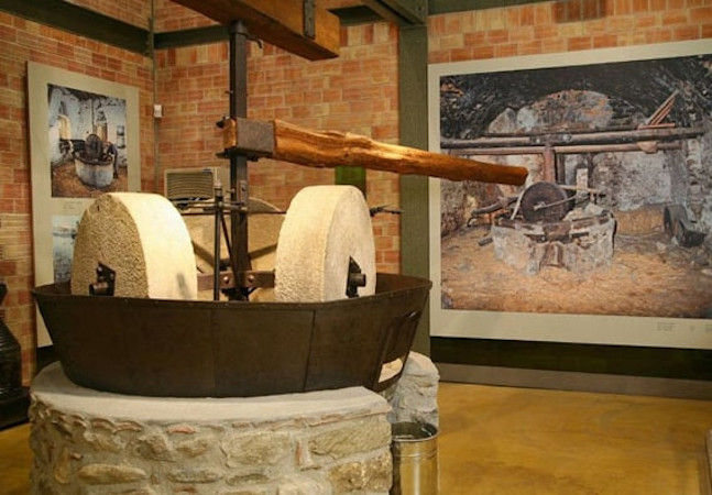 stone old olive press at Melas Epidauros and murals on the walls in the background