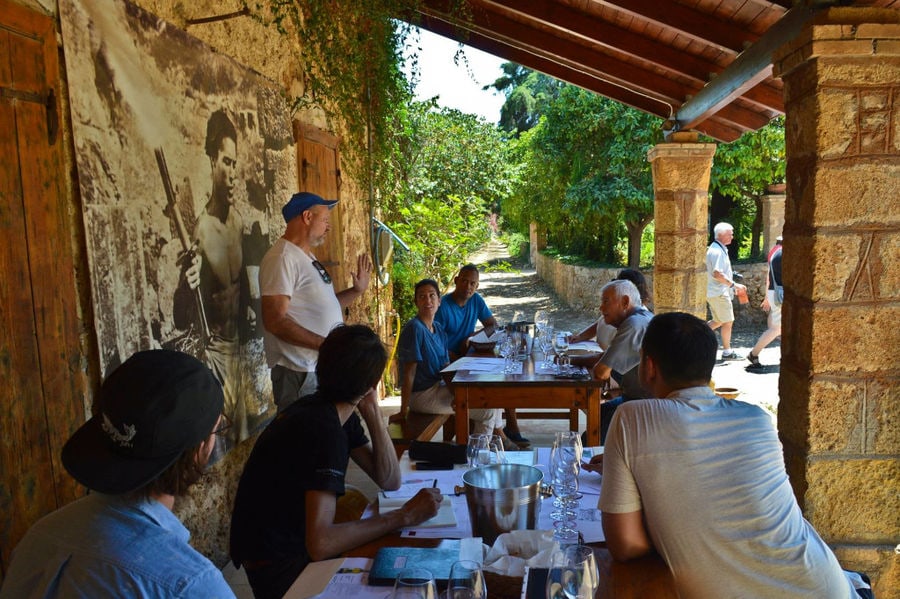 Tourists sitting on the tables and enjoy a wine tasting at 'Mercouri Estate' winery outside