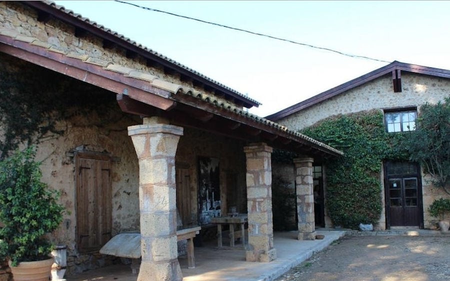 one side of the building with stone walls and plants of 'Mercouri Estate' winery