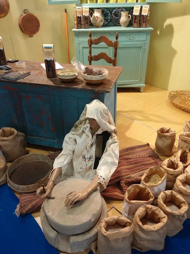 exhibit shows a woman using old stone mill at 'Pantazis Stone Flour Mill' museum