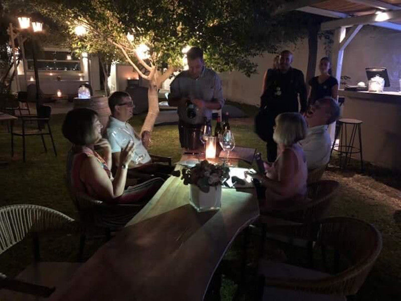 tourists tasting wine at 'Minos - Miliarakis Winery' outside by night