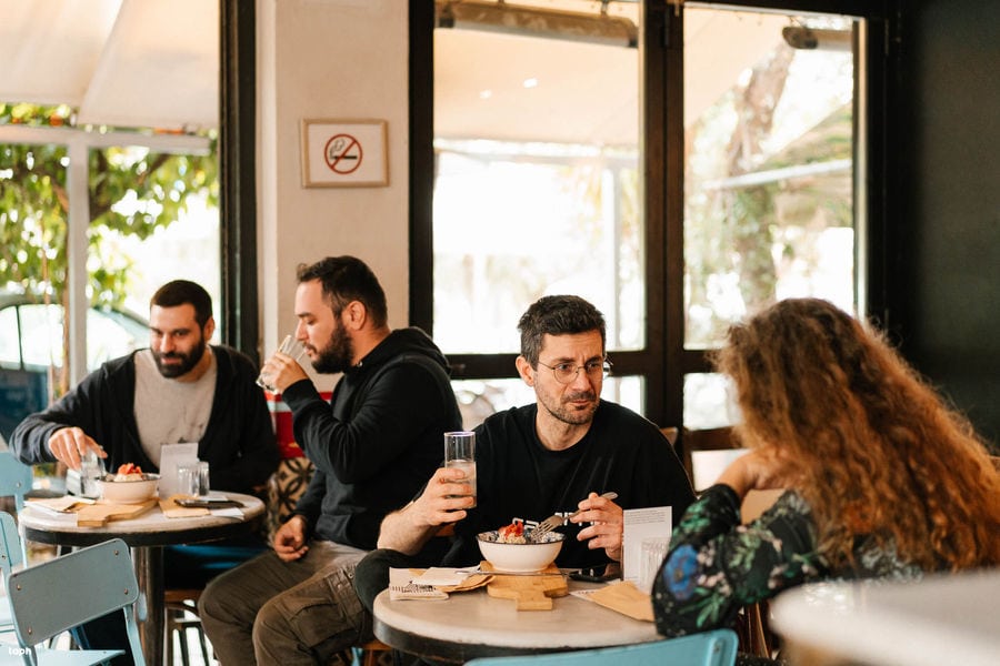 A captivating scene unfolds as people gather around tables, savoring delicious meals while being serenaded by enchanting melodies. Perfect harmony of food and music.