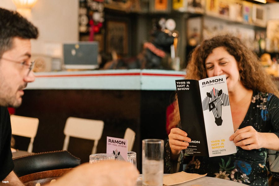 a woman immerses herself in the menu of Ramon Bar, contemplating the tantalizing choices that lie before her.