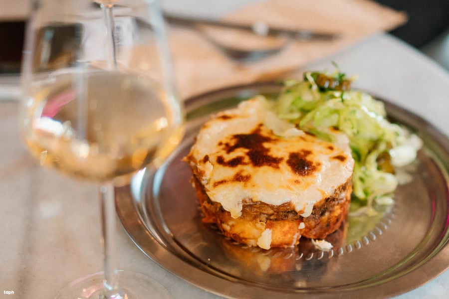 a golden-fried egg crowns a bed of crusty bread, accompanied by a vibrant side salad. A refreshing glass of rosé complements the feast.