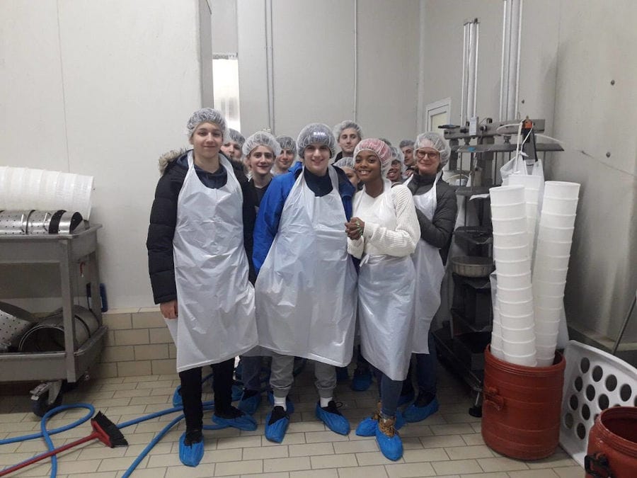 a group of young tourists smiling happily at the camera in 'Mystakelli Dairy' plant room