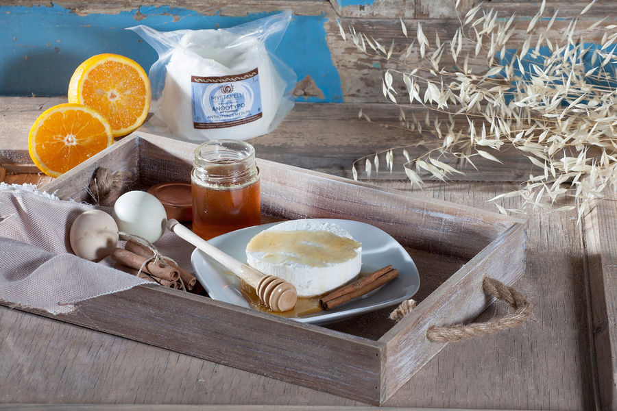 plate with 'Mystakelli Dairy' white cheese and honey and a cinnamon stick on wood plateau