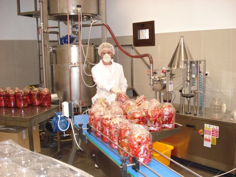 woman with disposable gloves stuffing red pepper with coleslaw at 'Naoumidis All Peppers' plant