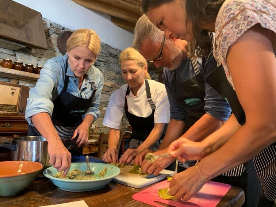 a man and three women cooking around the table at 'Narlis Farm' kitchen