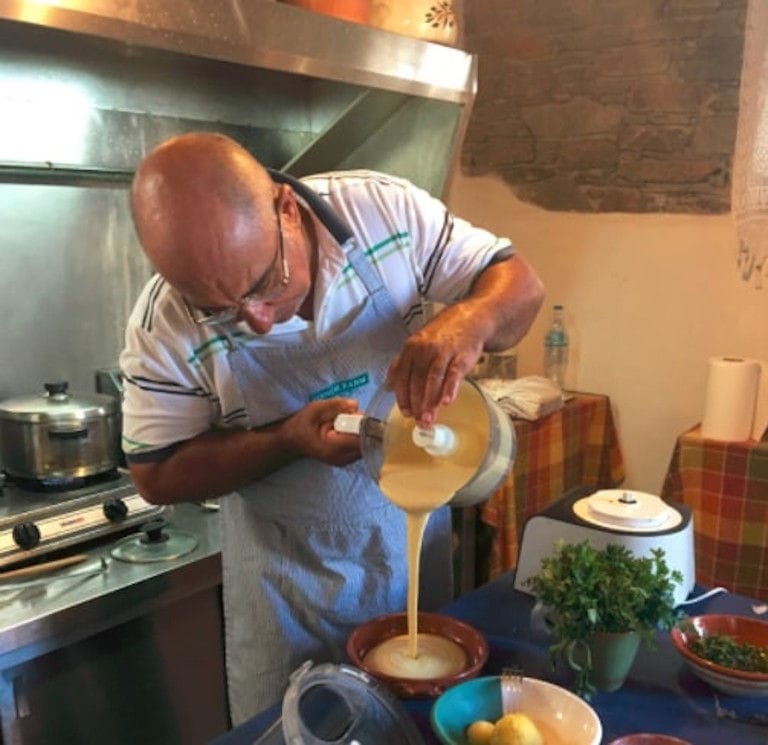 man putting pancake composition in ceramic pot from the mixer bowl at 'Narlis Farm' kitchen with electric stove in the background