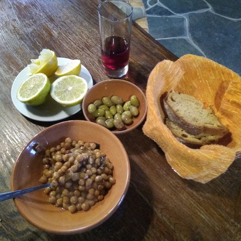 ceramic bowls with cooked chickpeas, bread, half lemons and a glass of wine at 'Narlis Farm'
