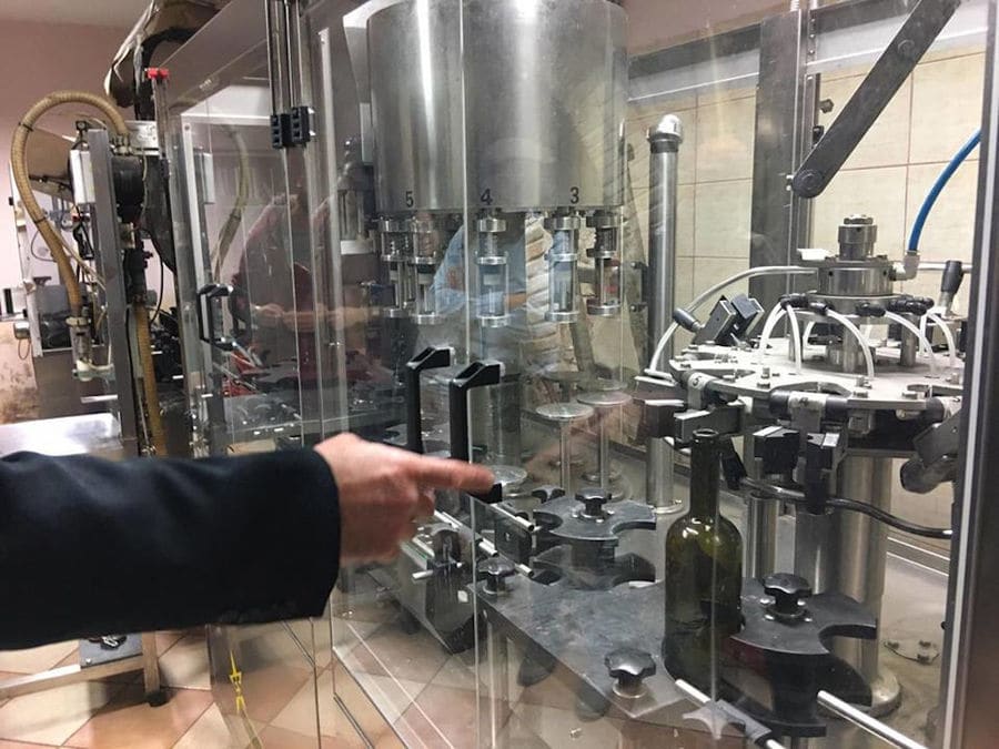 man working wine labeling machine at Nikolou Winery plant