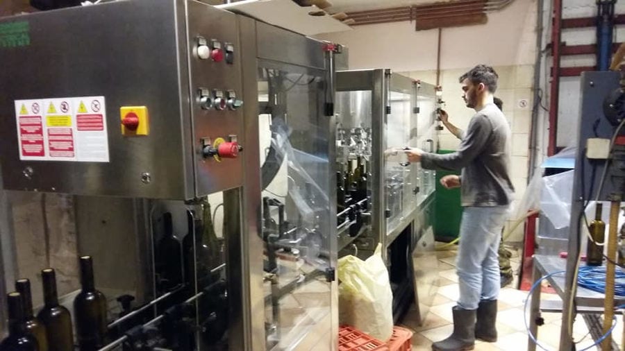 boy working wine packaging machine at Nikolou Winery plant
