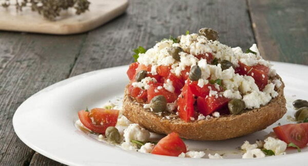 Plate with Greek ‘dakos’ like dry bread made with barley with pieces of tomato and white cheese on top