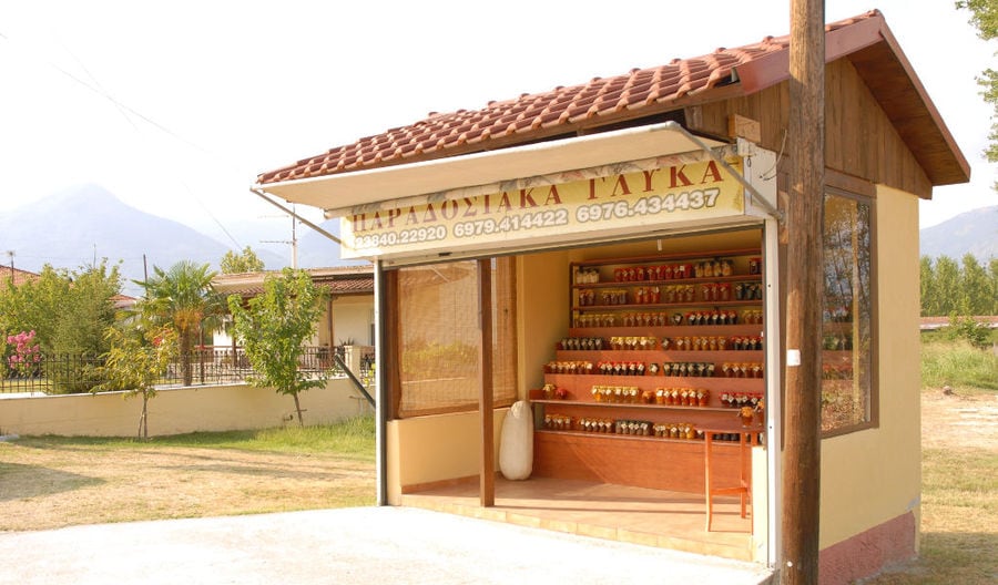 a wood kiosk with shelves on the top of each others with jars with marmelades from 'Voskopoulos Handicraft'